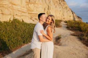 A couple shares a tender moment on a scenic coastal path.