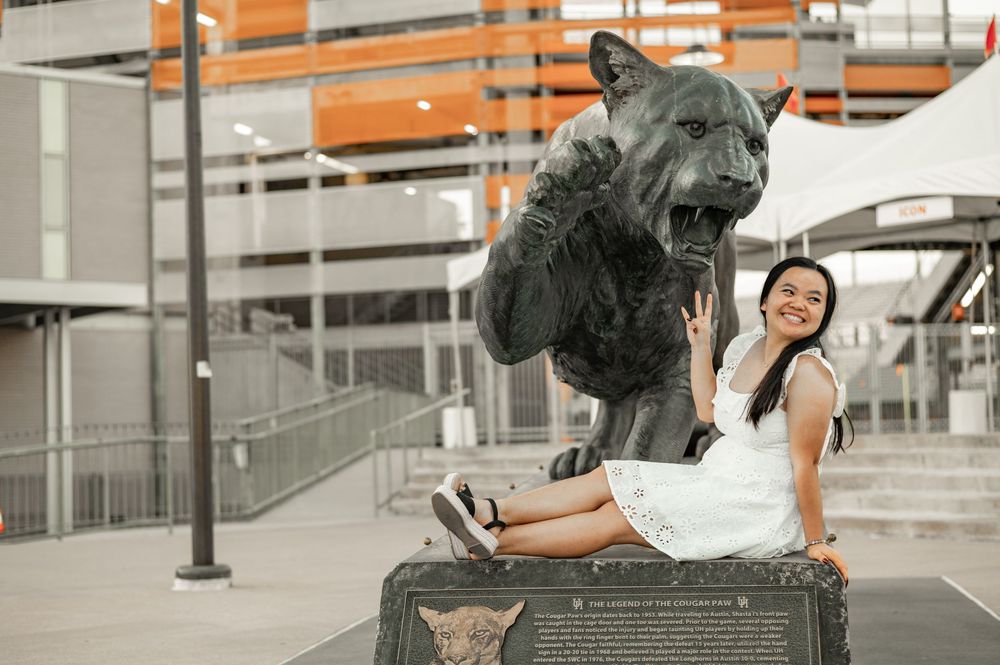 A large bronze bear statue stands guard outside a modern building with metal railings and orange accents.