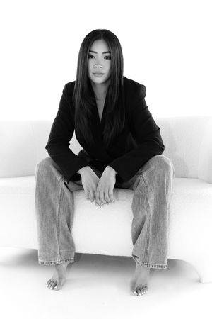 Black and white artistic photo series showing women in black blazers and jeans sitting on white surface.