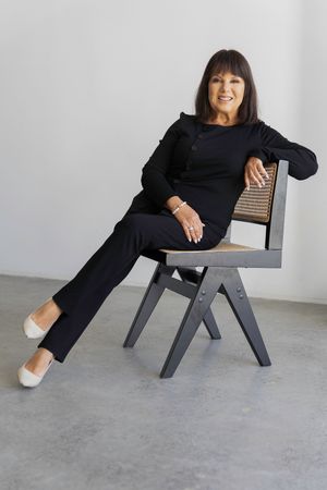 A series of four photos showing someone in a black outfit reclining on a modern grey wooden chair against a white wall.