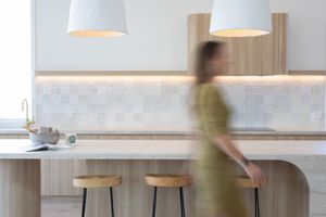 Modern pendant lamps with white shades hang from the ceiling in a minimalist dining space.