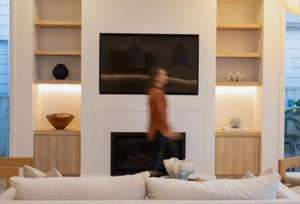 Modern white living room interior with built-in shelving and wall-mounted TV features clean lines and minimalist decor.
