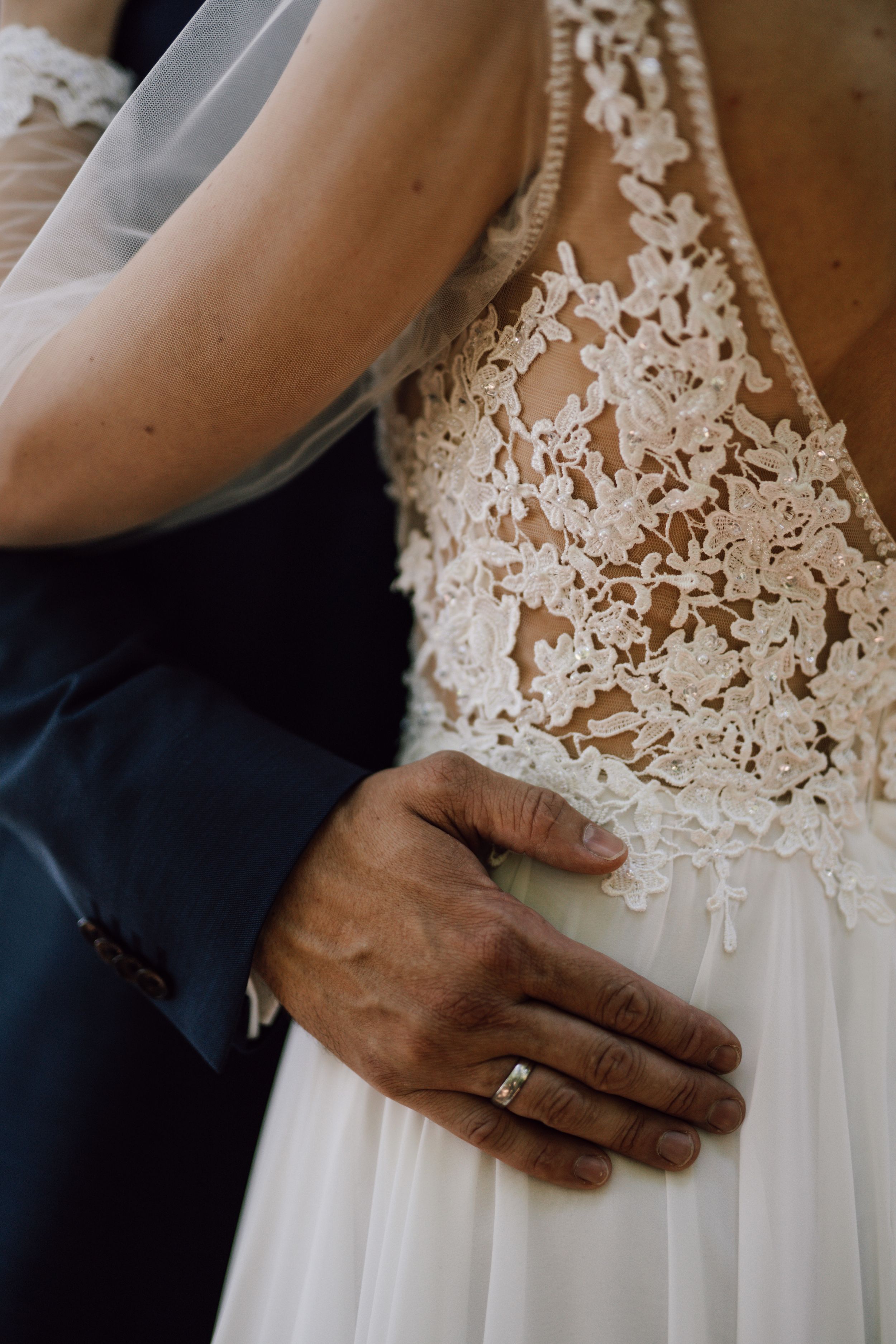 Close-up detail of intricate lace wedding dress and formal suit.