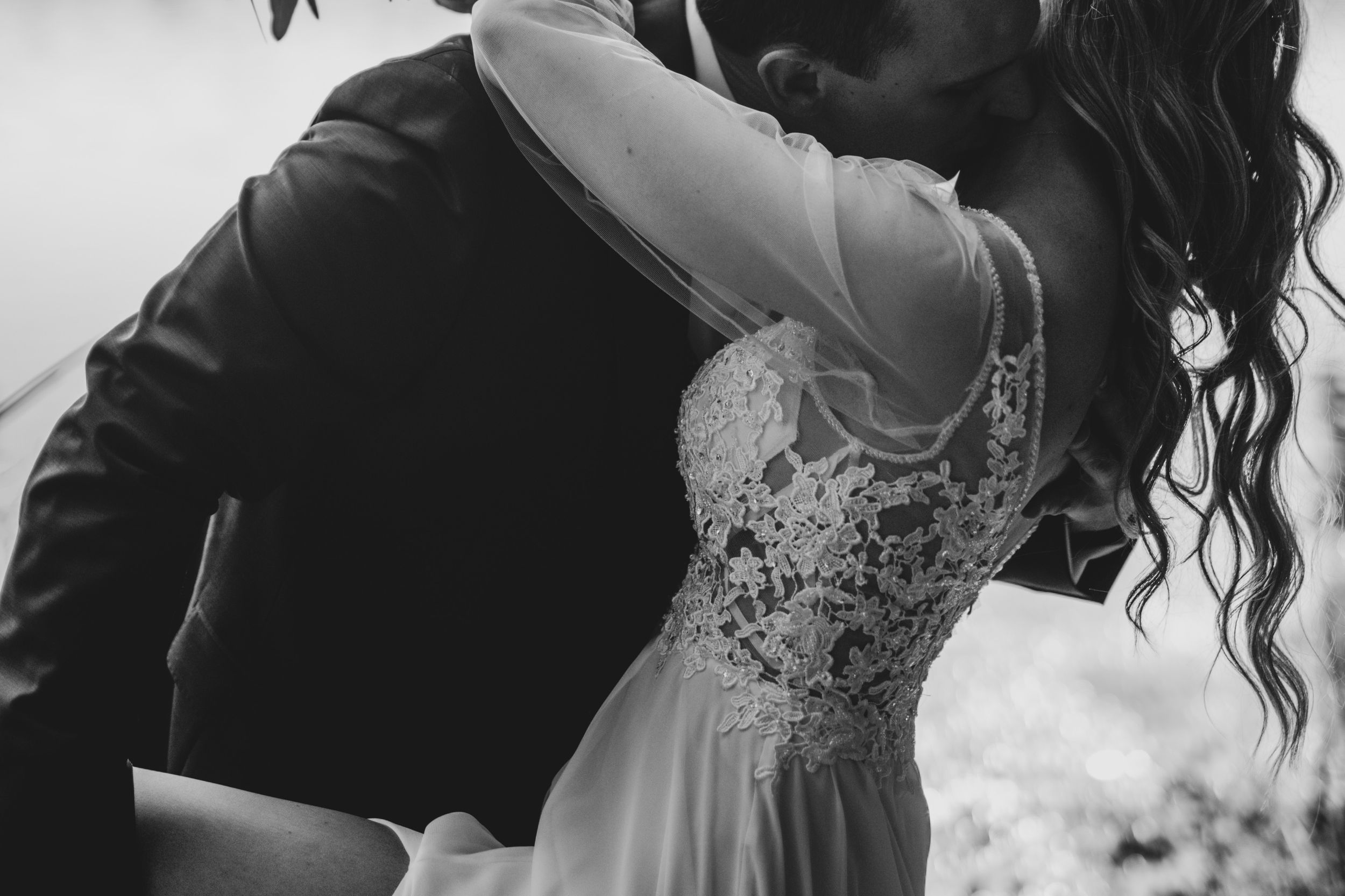 Black and white portrait showing the intricate details of a wedding dress and embrace.