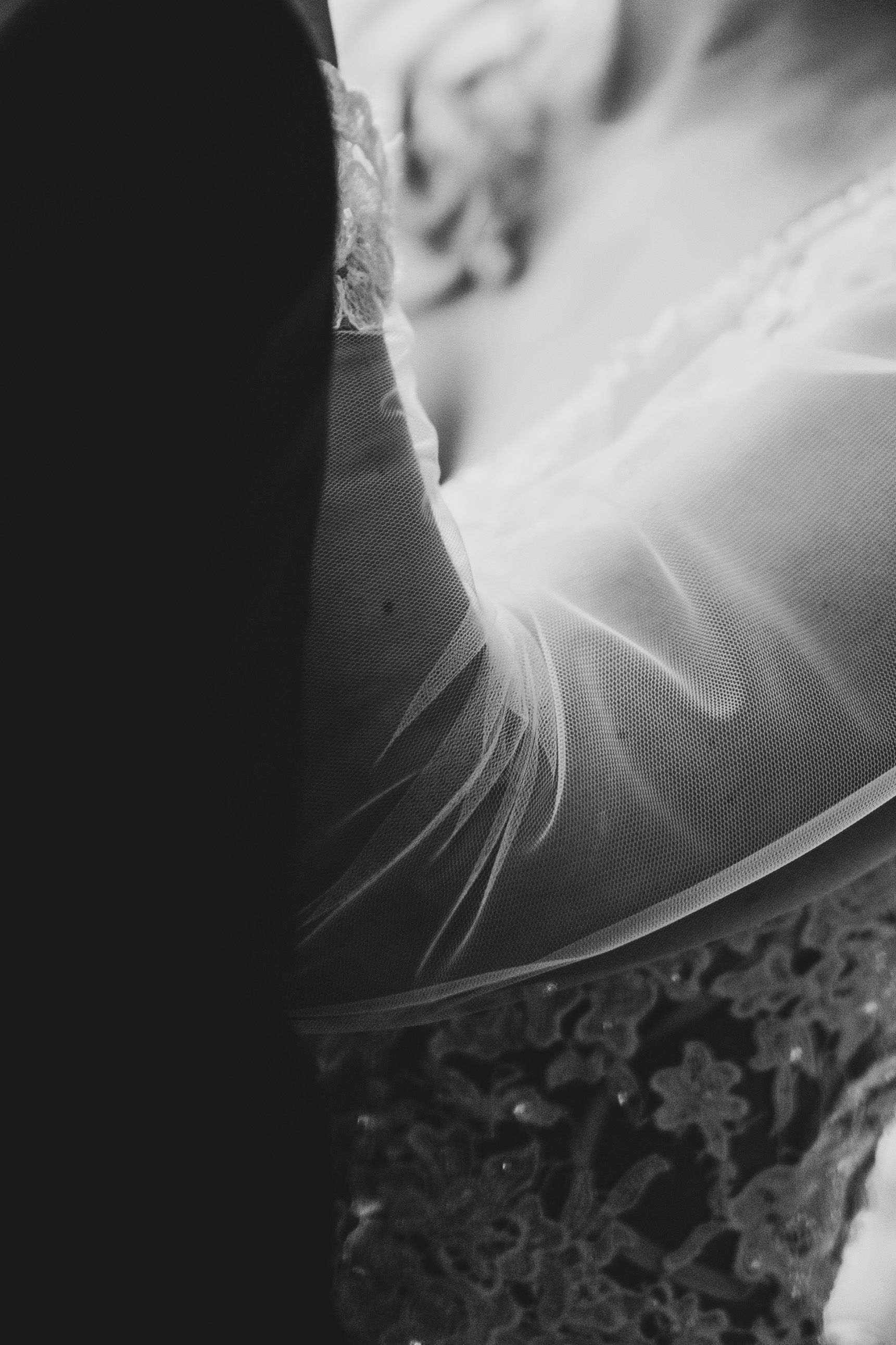 Black and white close-up of wedding dress lace and veil details.
