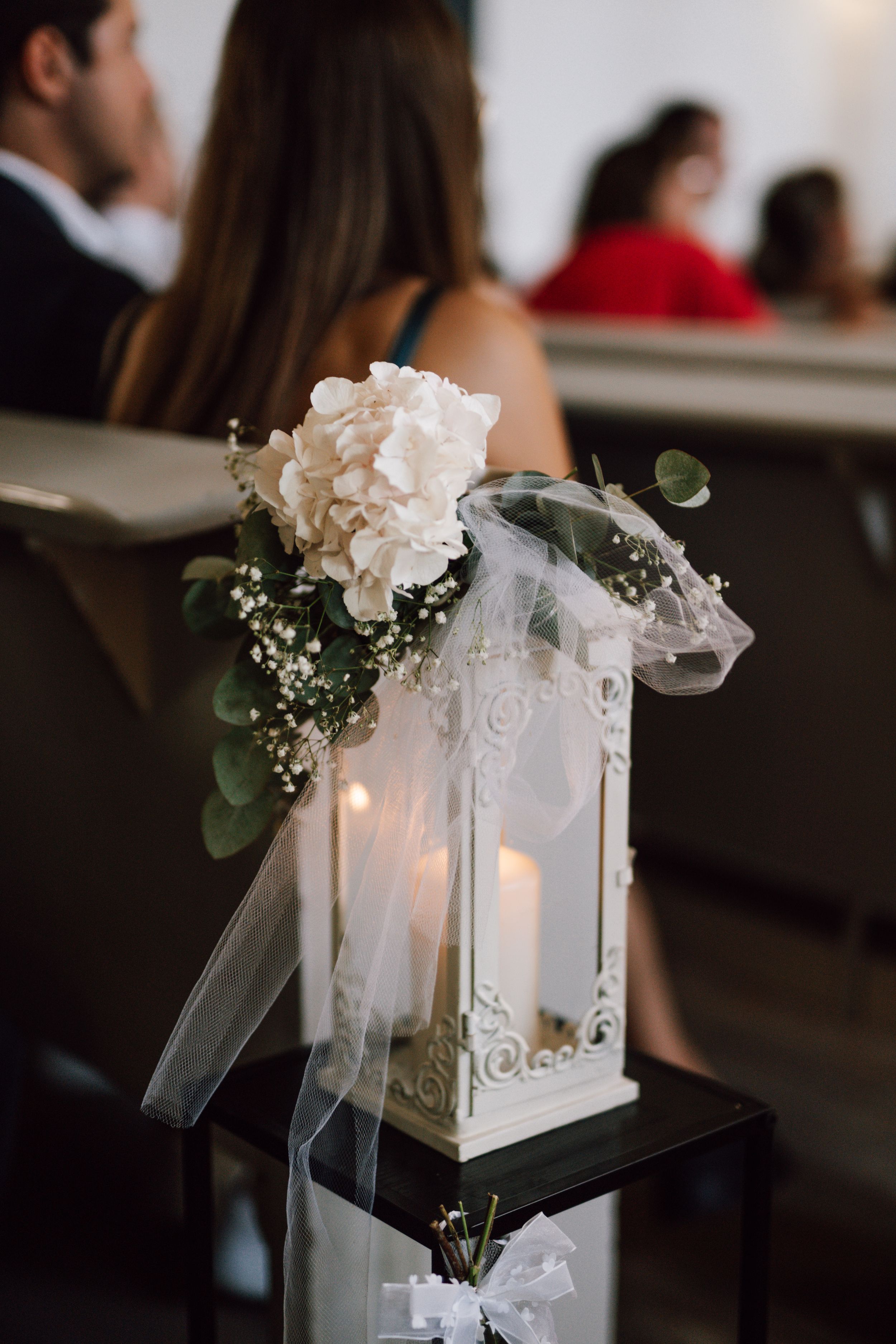 Elegant white lantern centerpiece decorated with flowers and tulle at a wedding reception.