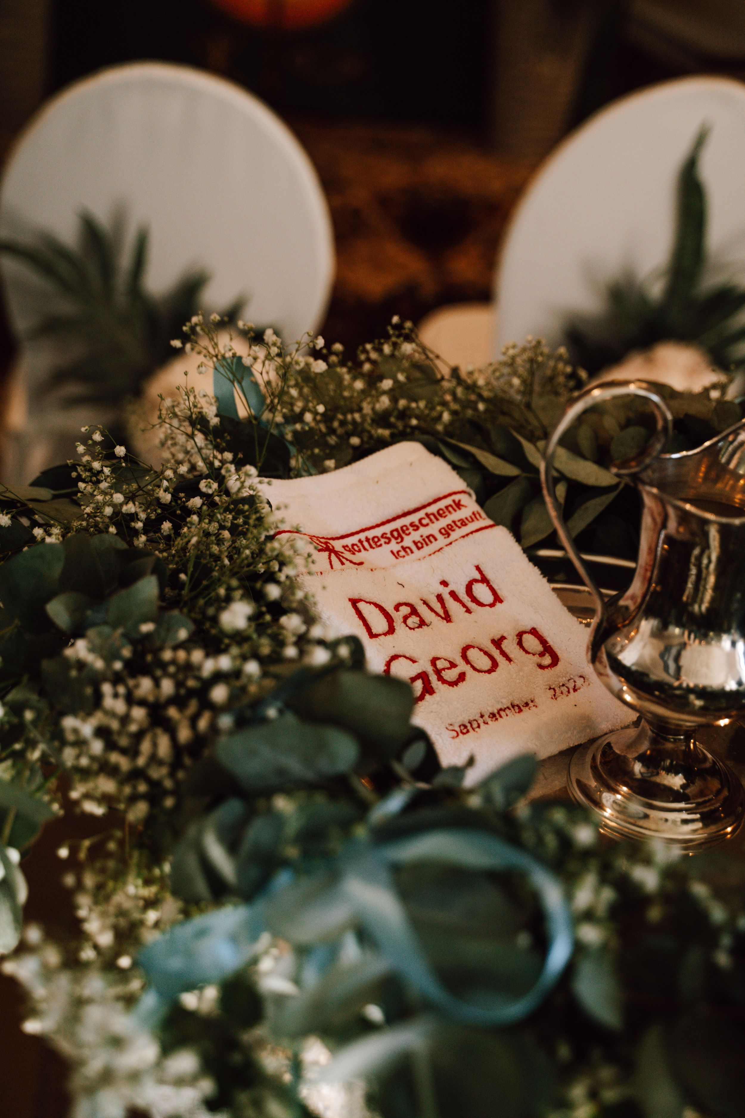 Wedding place cards with names nestled among greenery and baby's breath decorations.