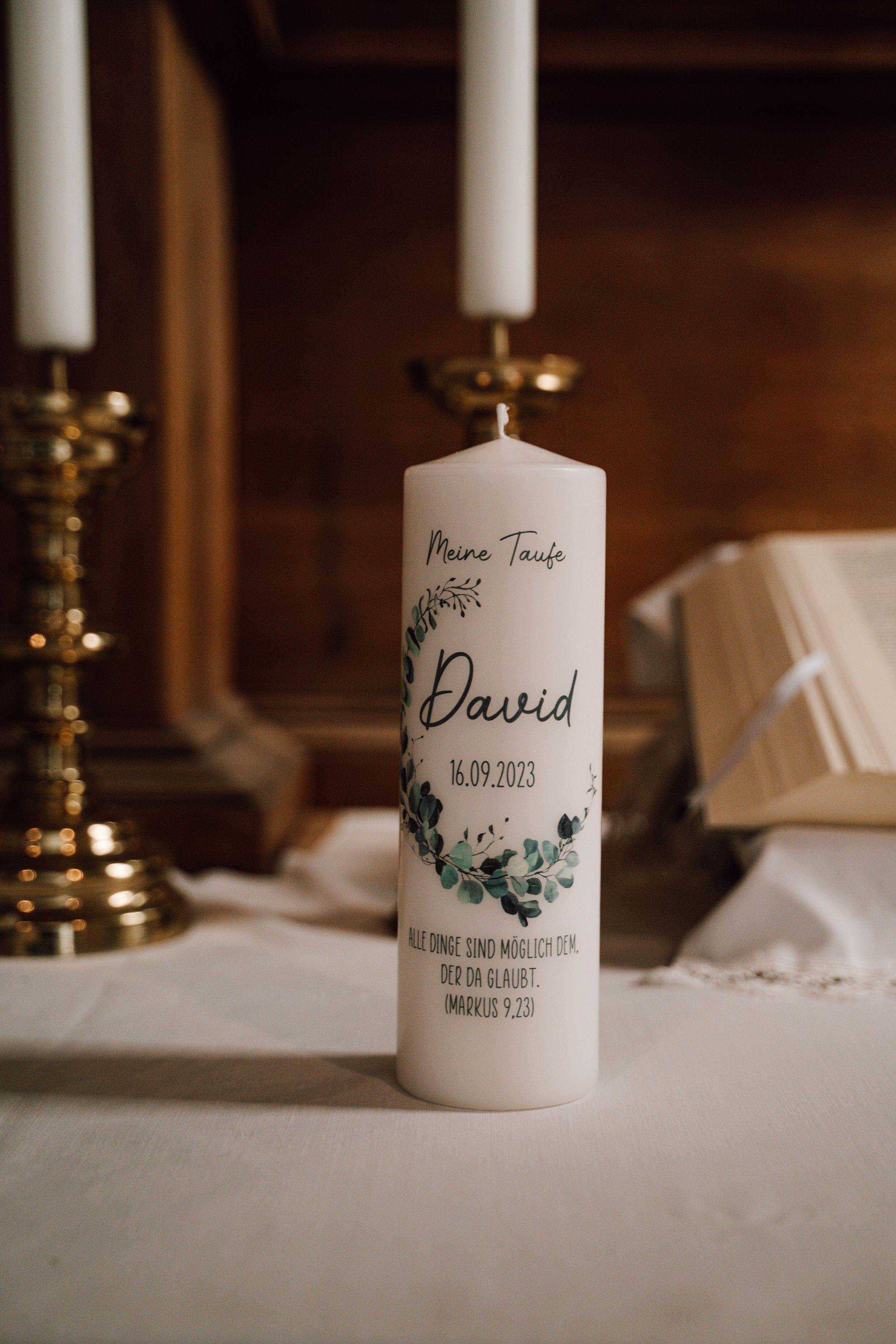 Personalized wedding candles with names and floral designs displayed on white linen.
