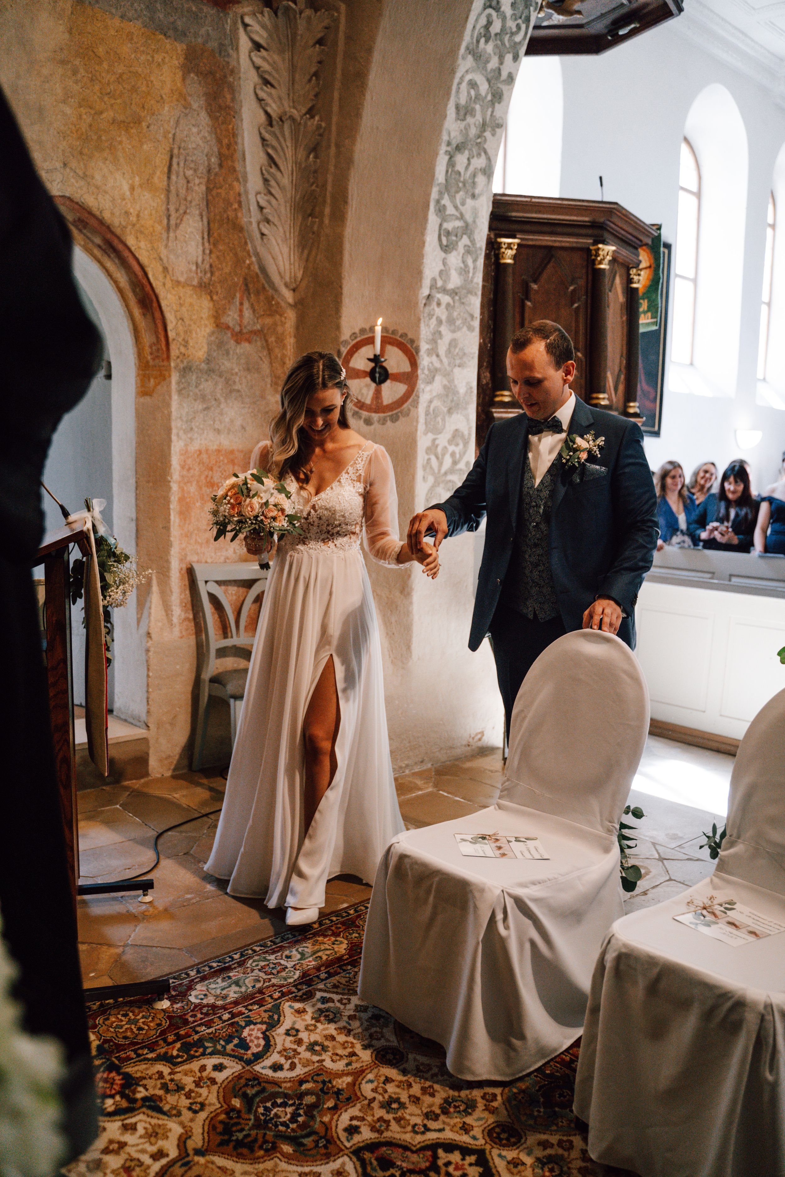 Church ceremony setup with white covered chairs and stone archways.
