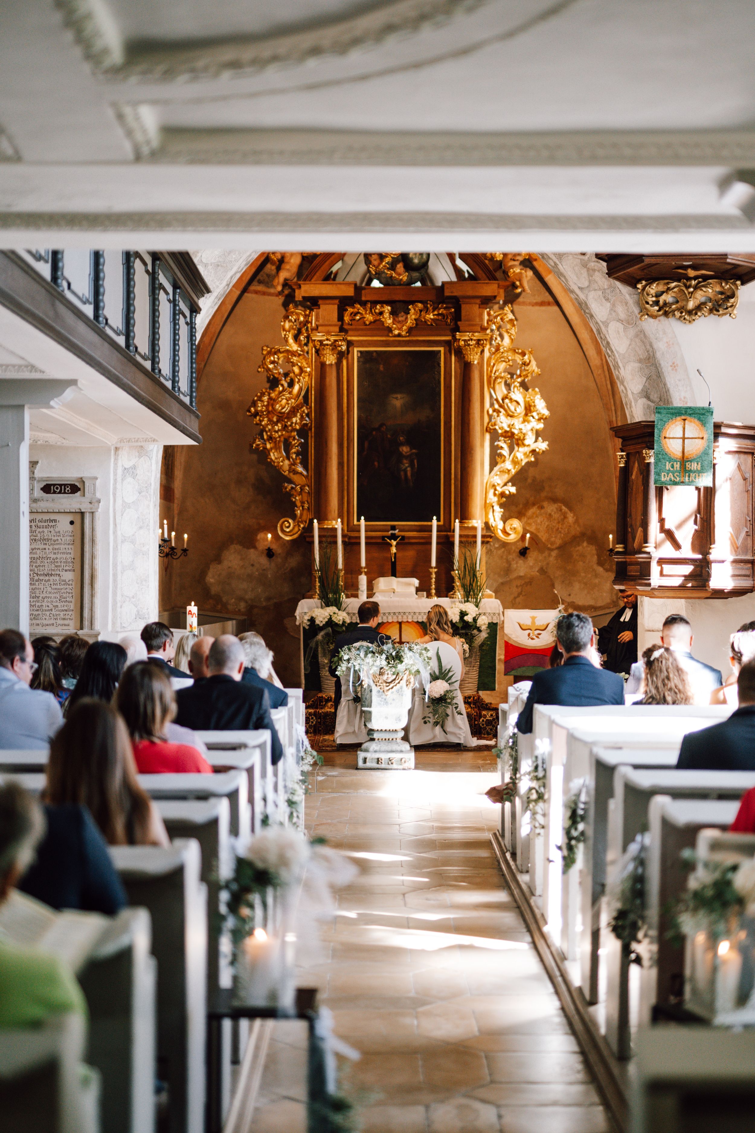 Traditional church interior decorated for wedding with golden altar and floral arrangements.