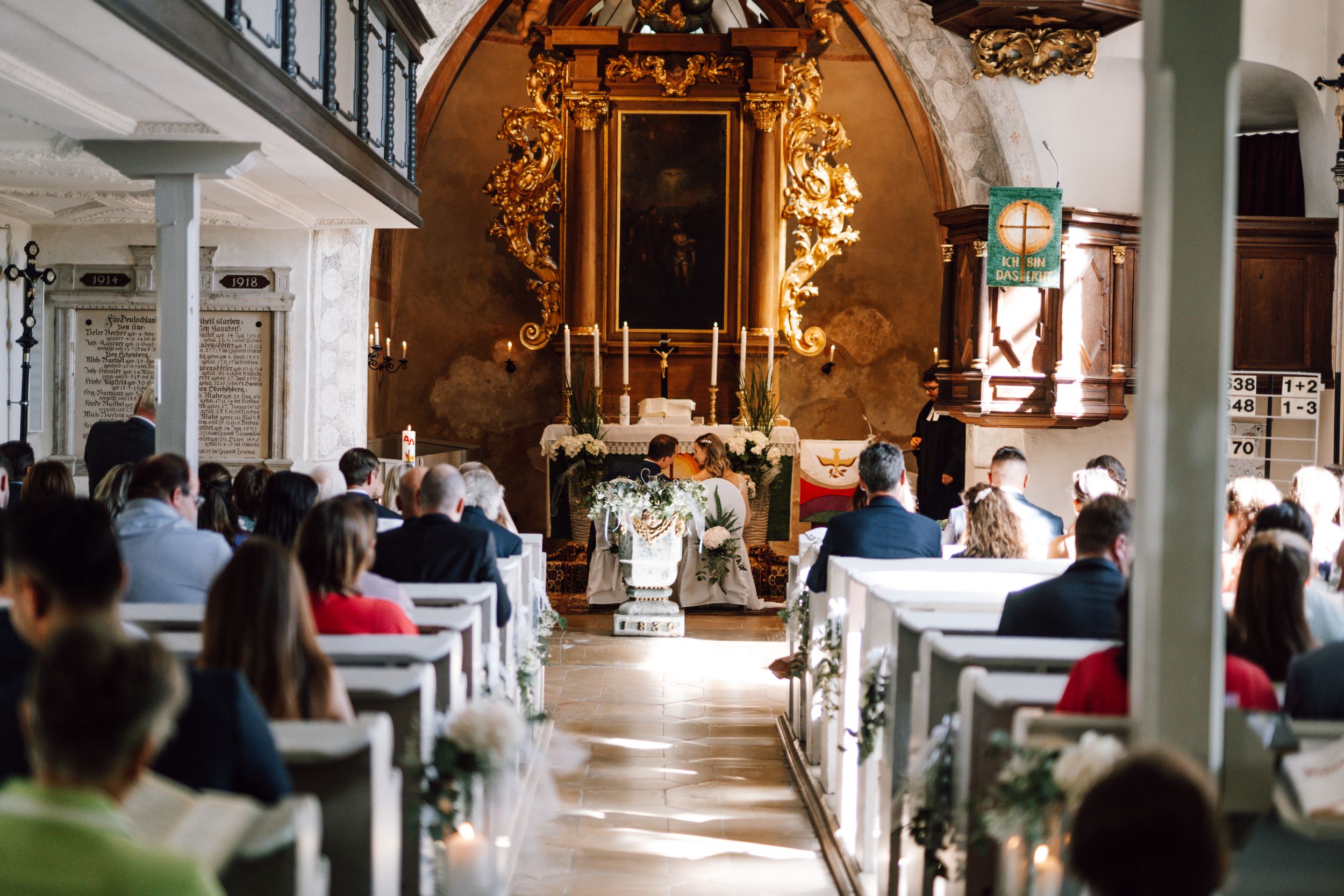 Elegant church ceremony space with ornate golden altar and rows of guest seating.