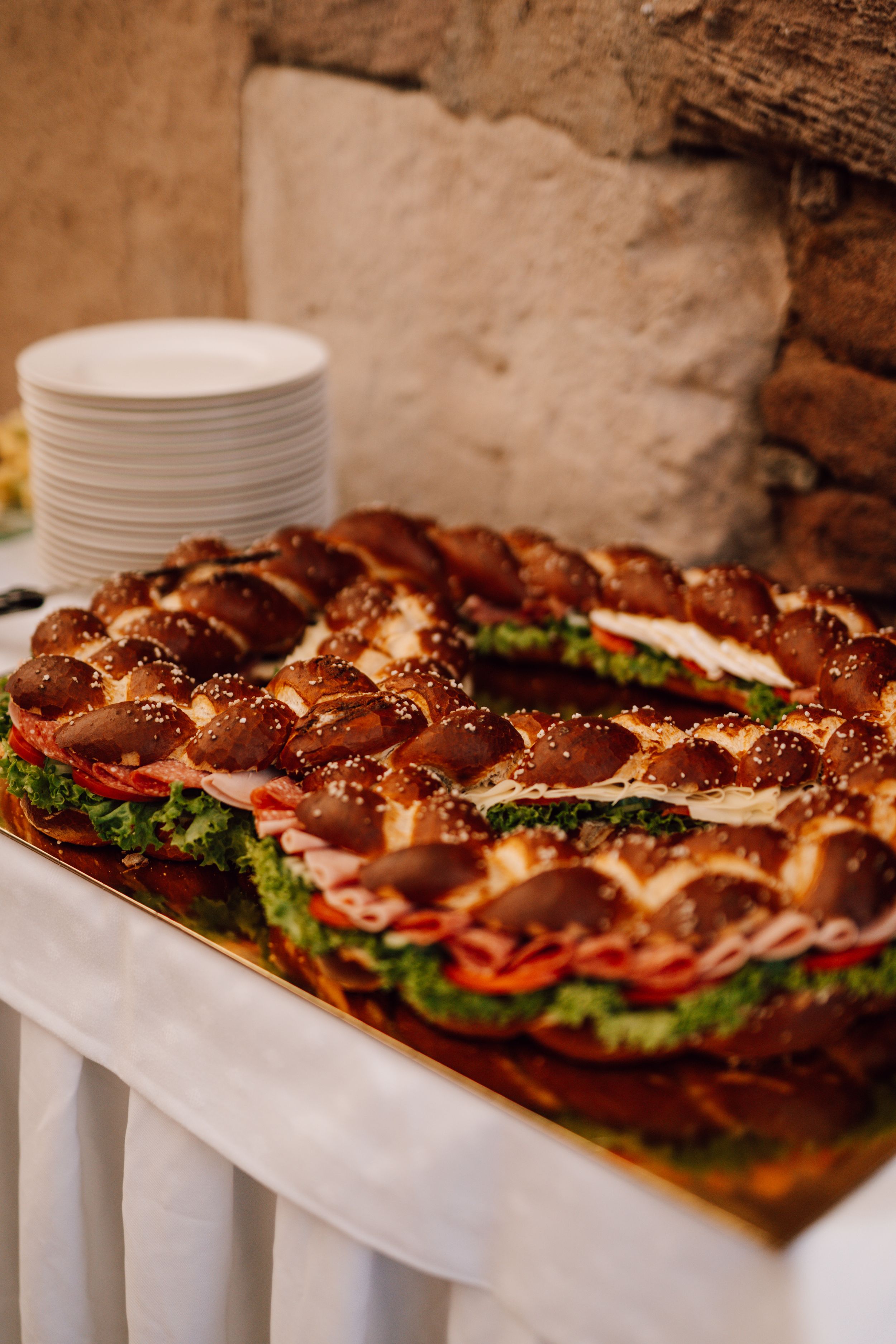 Long display of pretzel rolls and sandwiches on white serving tables.