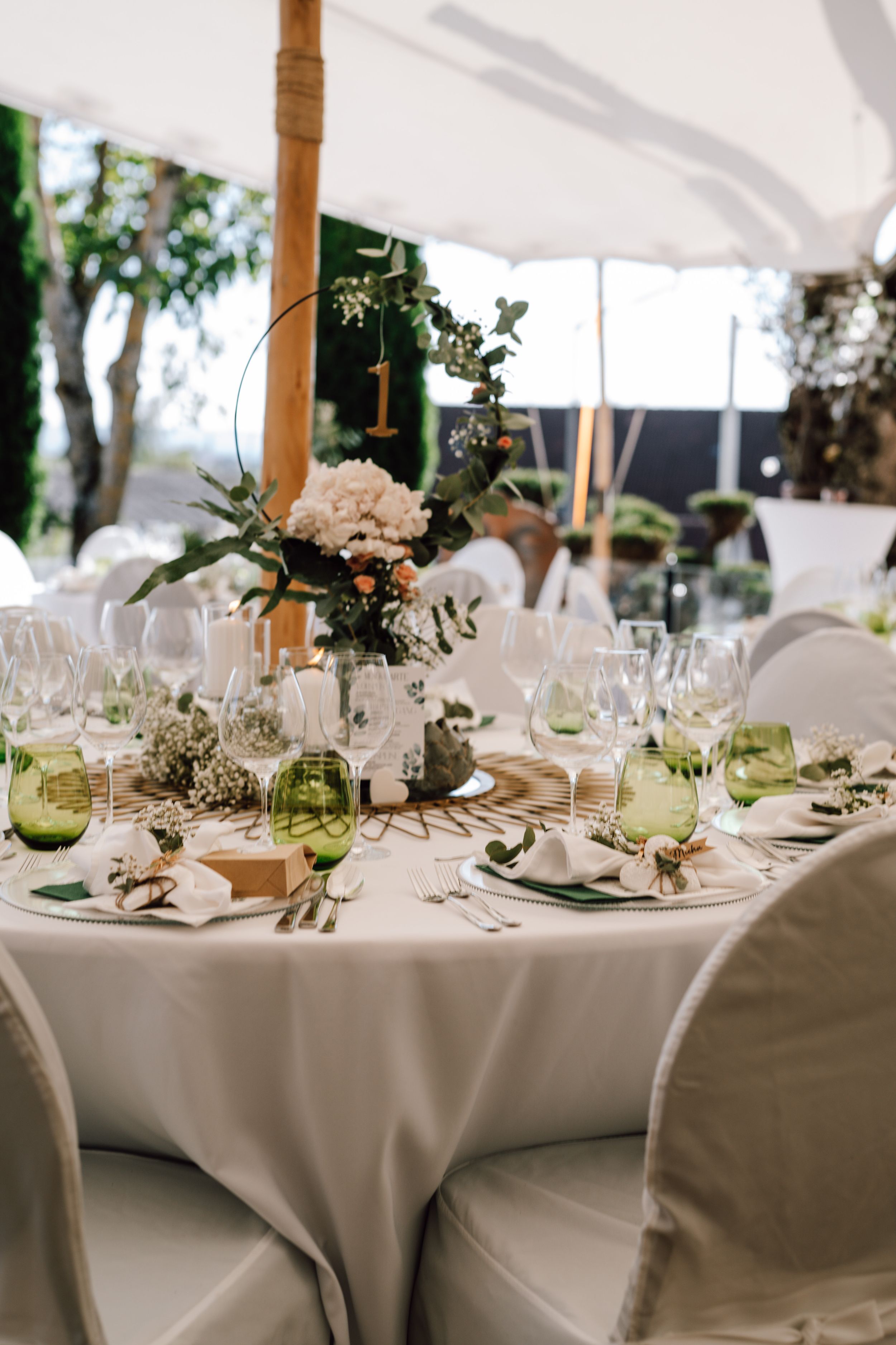 Wedding reception tables set with white linens, glassware and delicate floral centerpieces.