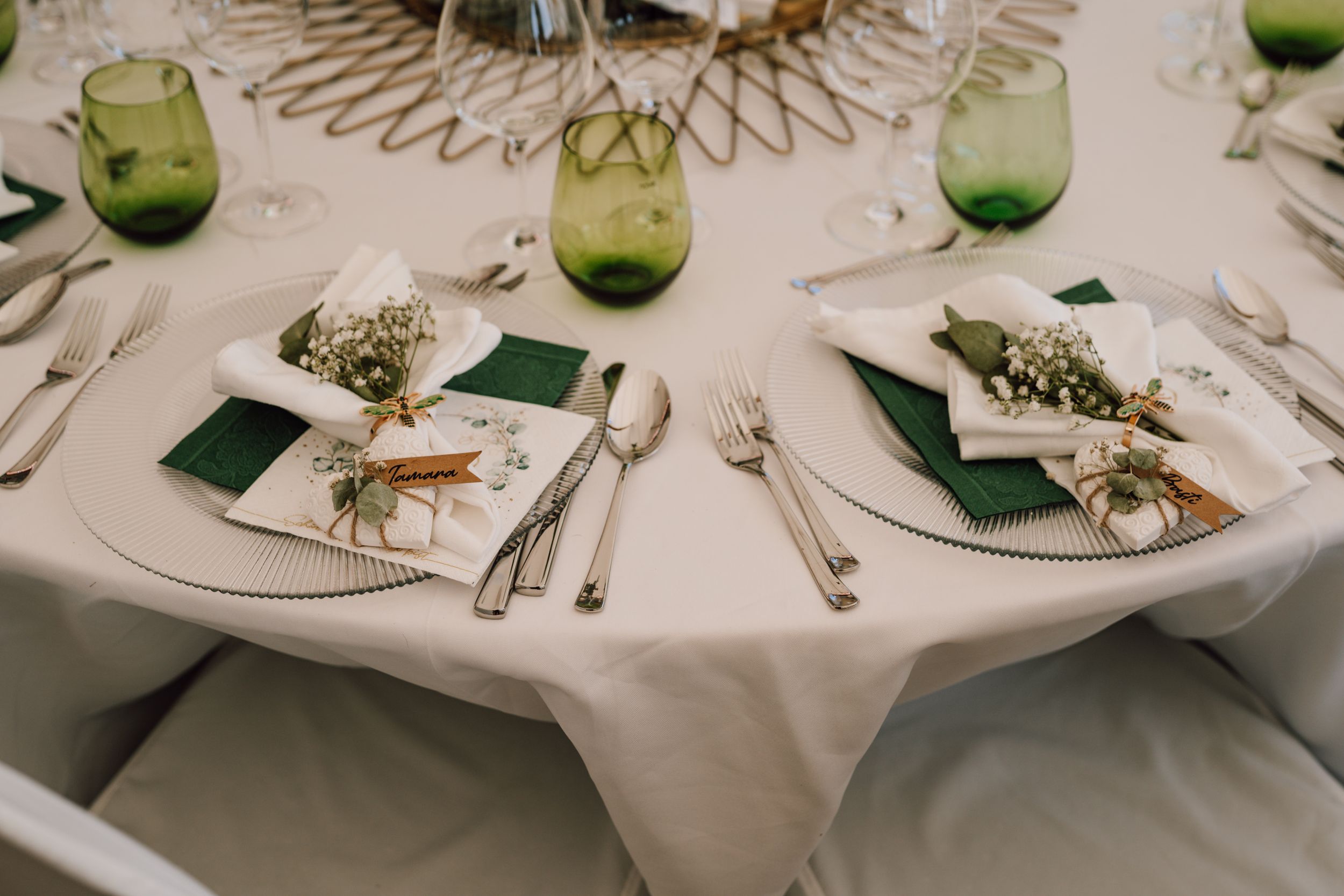 Elegant wedding table settings with green accents and white linens create a sophisticated dining atmosphere.
