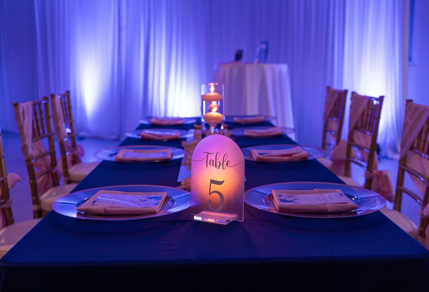 Elegant table setting with blue uplighting and illuminated bottle centerpiece.