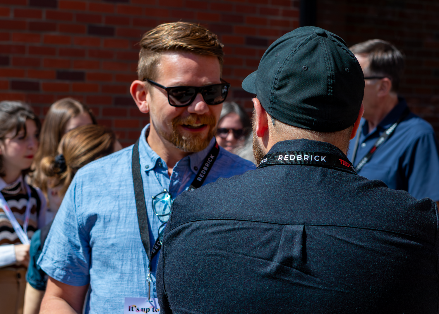 Two attendees in casual attire having an animated conversation at an outdoor event.