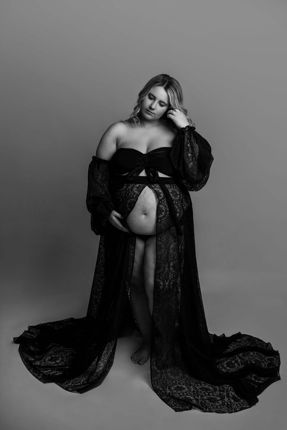 Artistic black and white maternity photo with long lace robe and bare belly.