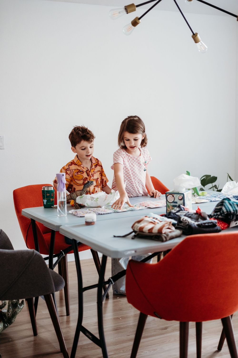 Brother and sister sit at a dining room table finishing breakfast before the official photo session starts.
