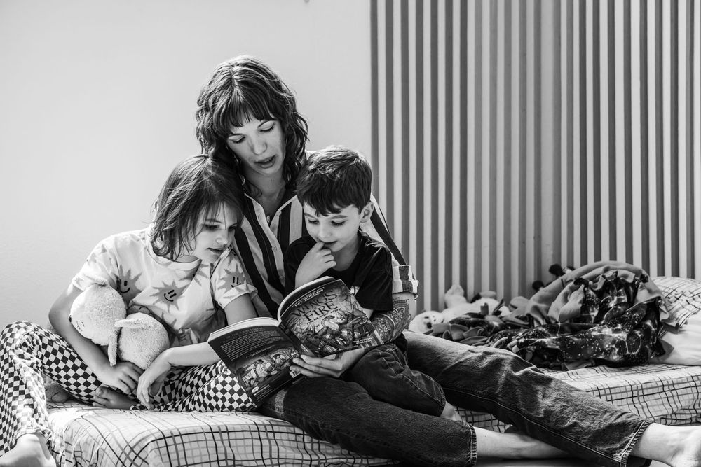 Black and white image of a mother with her children sitting together reading a book
