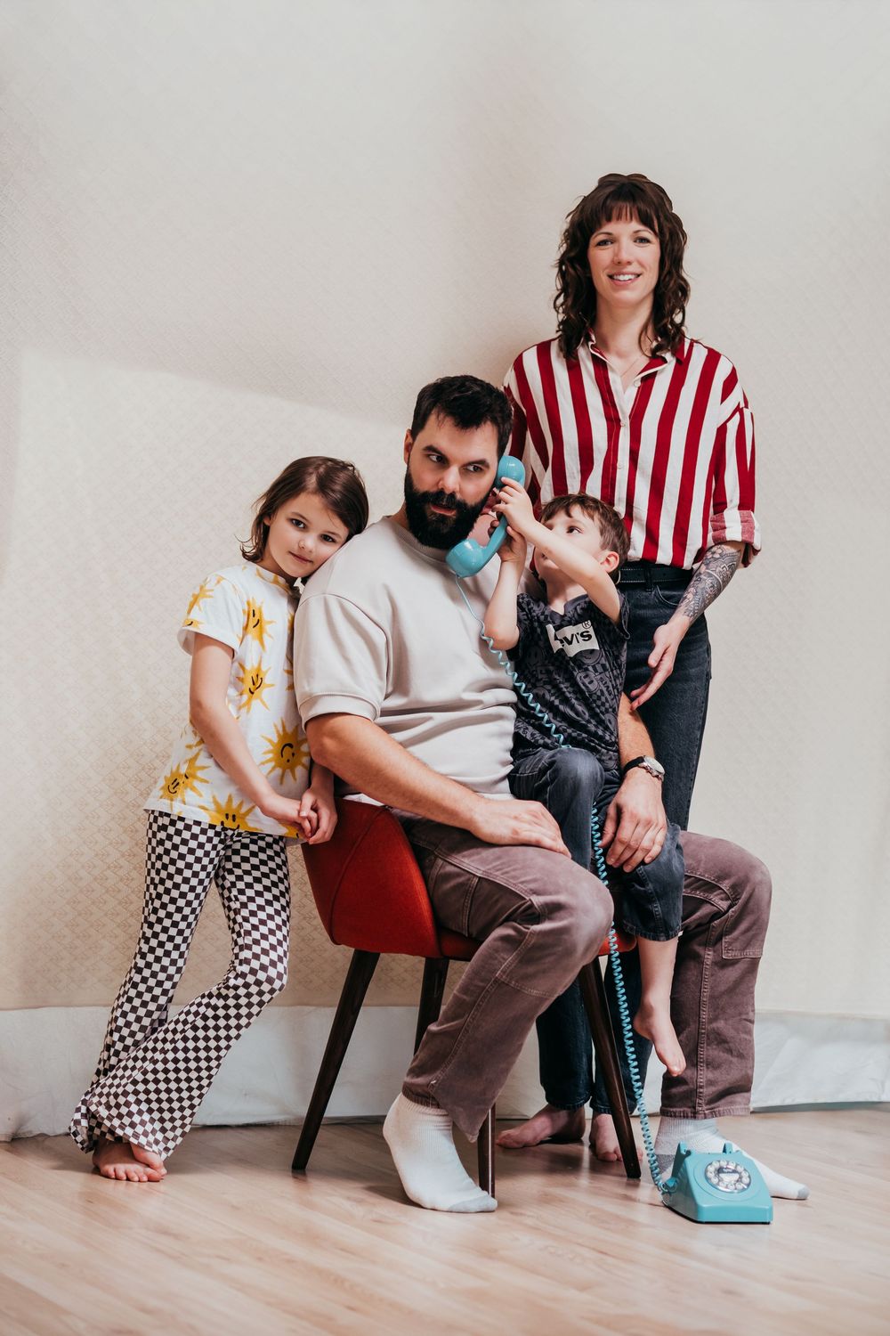 A family of 4 sits for a relaxed formal portrait in their home.