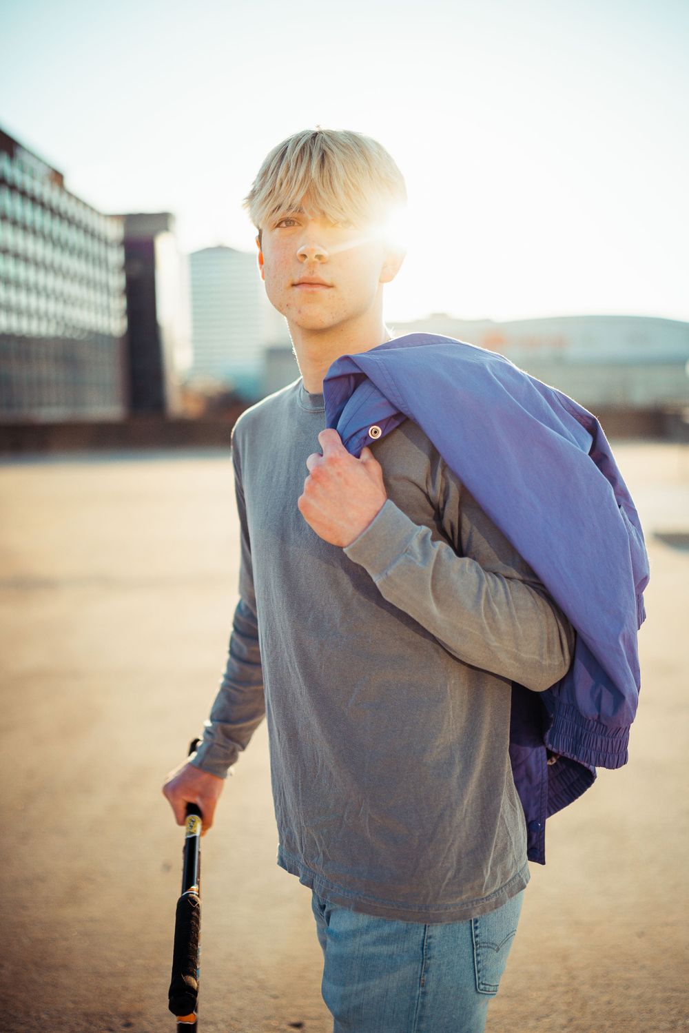 Student wearing grey sweater and backpack photographed during golden hour in an urban setting.