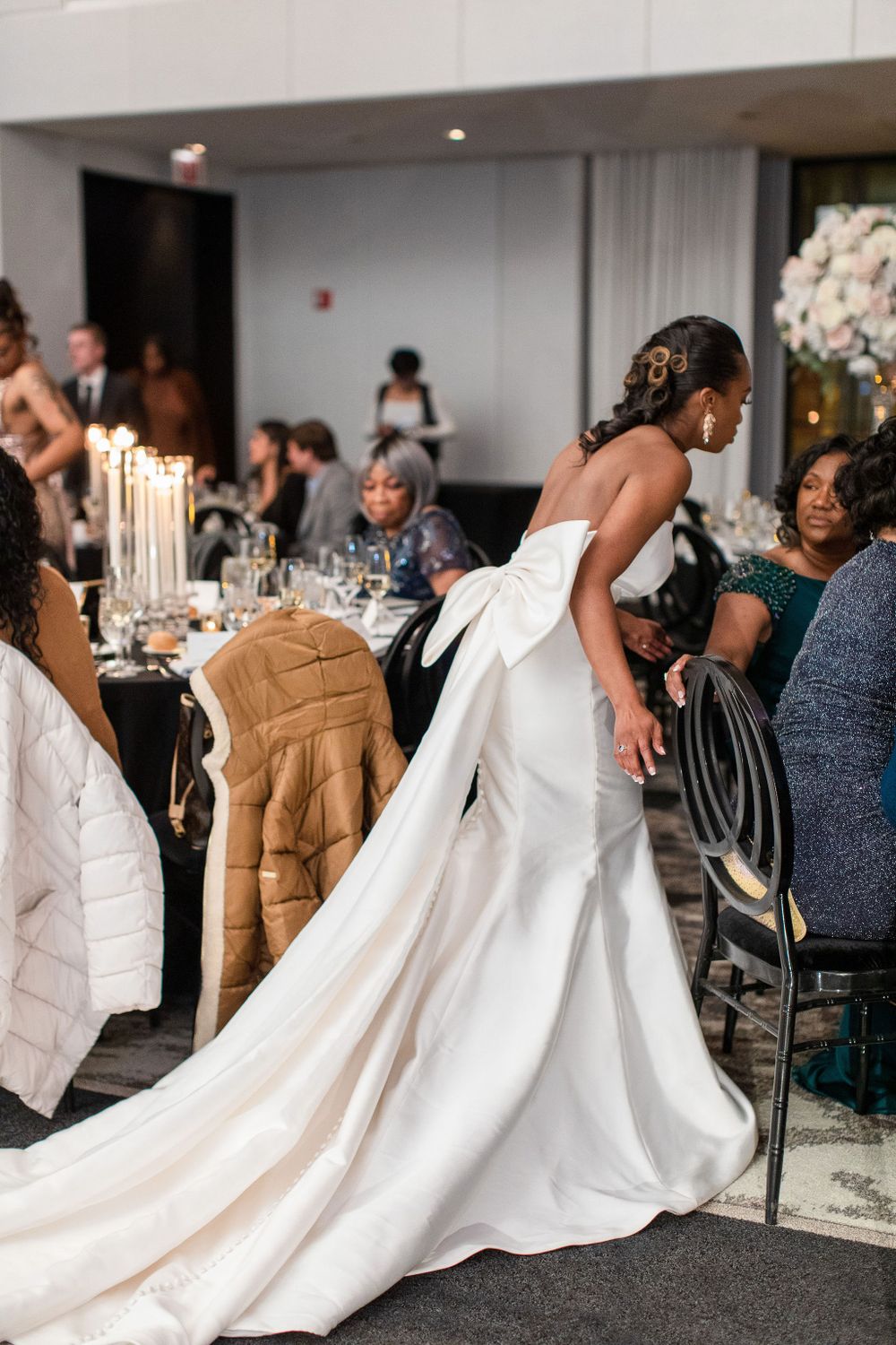 An elegant white wedding dress with a dramatic train flows behind as the wearer mingles with reception guests.