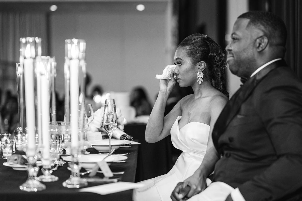 A touching emotional moment during a wedding reception dinner with elegant candle centerpieces.