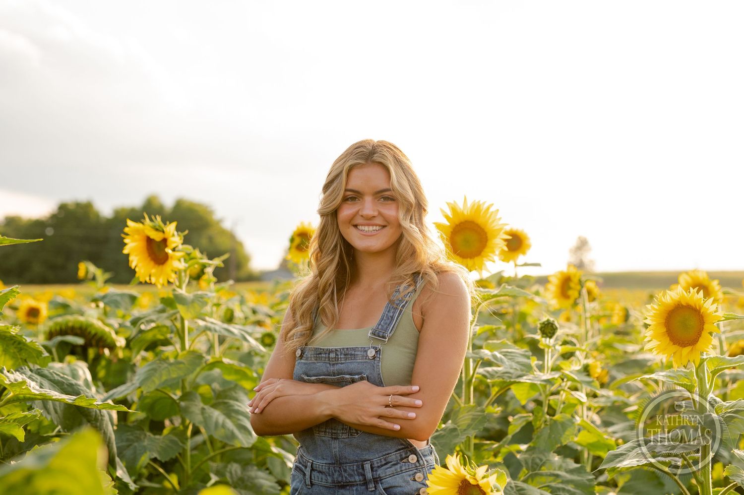 A casual outdoor portrait with bright sunflowers and warm evening light in the background.