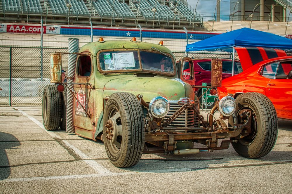 Vintage hot rod truck with exposed engine and custom modifications parked at car show.