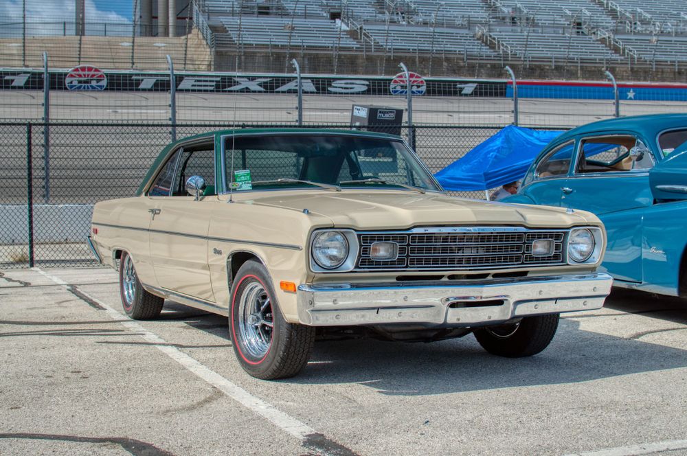 Classic 1960s Chevrolet Nova in cream color displayed at outdoor auto show.
