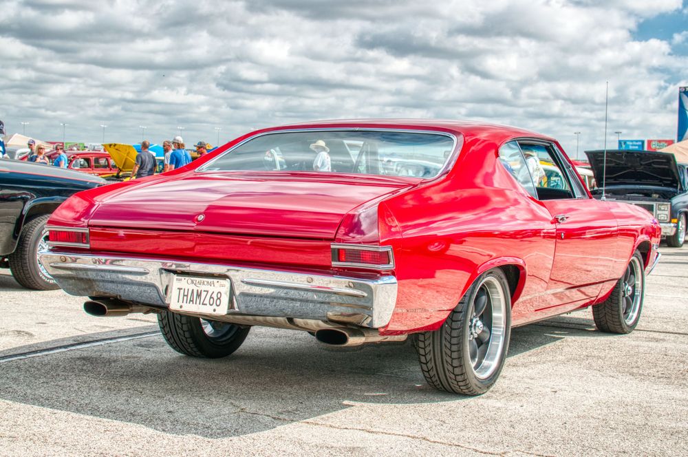 Red vintage Buick Riviera classic car with chrome trim shown from multiple angles at an outdoor car show.