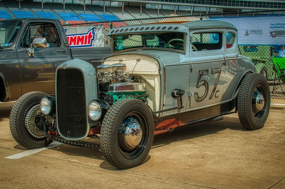 Vintage hot rod with raw metal finish and traditional hot rod styling at car show.