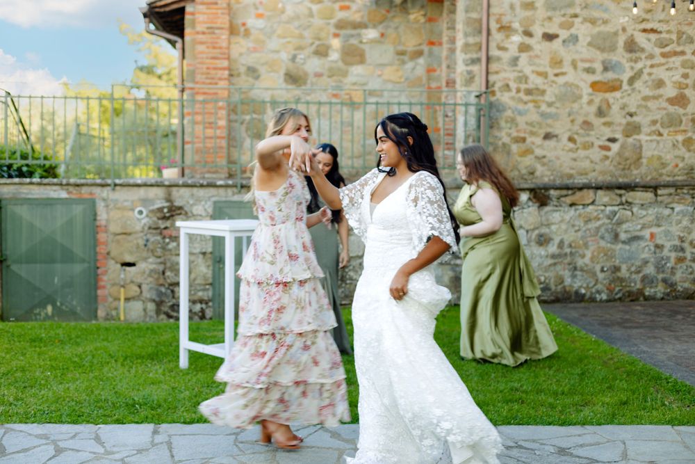 Wedding guests dance and celebrate on a stone patio outside a rustic villa.