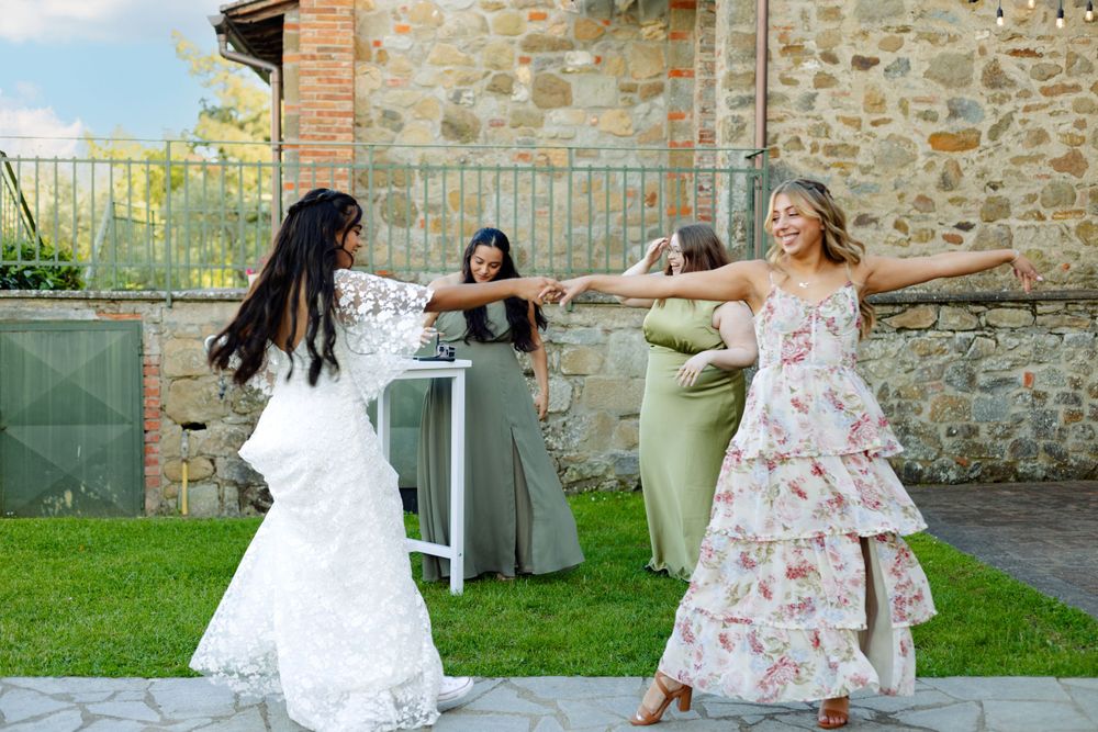 Wedding guests dancing joyfully on an outdoor patio near a stone villa.