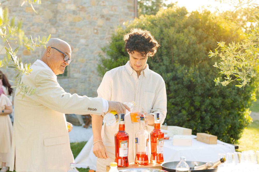 Drinks being poured and arranged at an outdoor event with rosé wine bottles in golden sunset light.