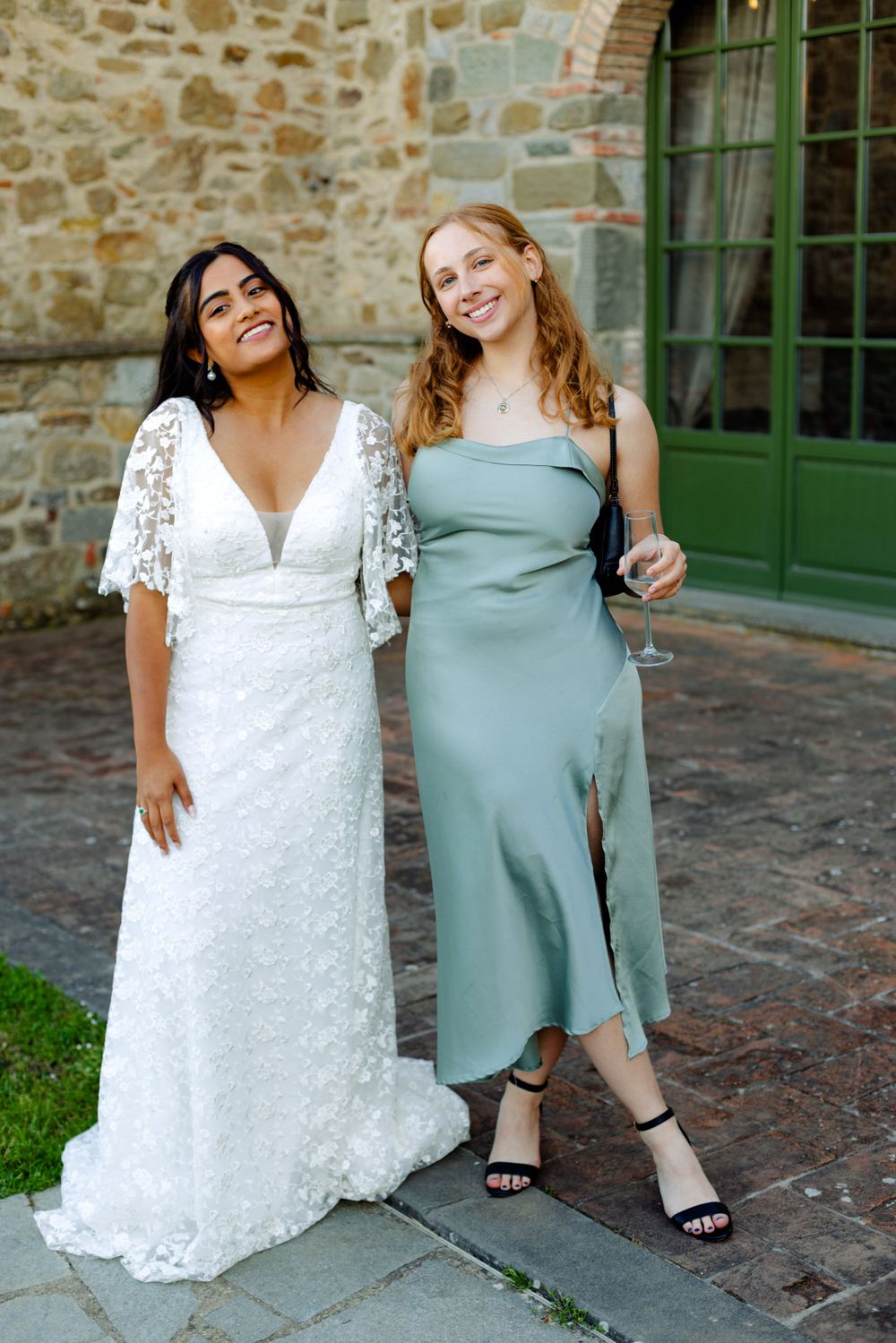 Two friends in elegant dresses posing together at a formal event.