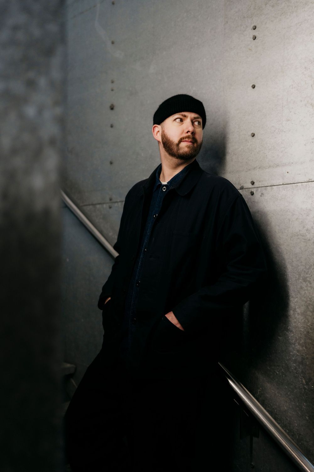 Person in black clothing against concrete wall in dramatic noir-style portrait sequence.