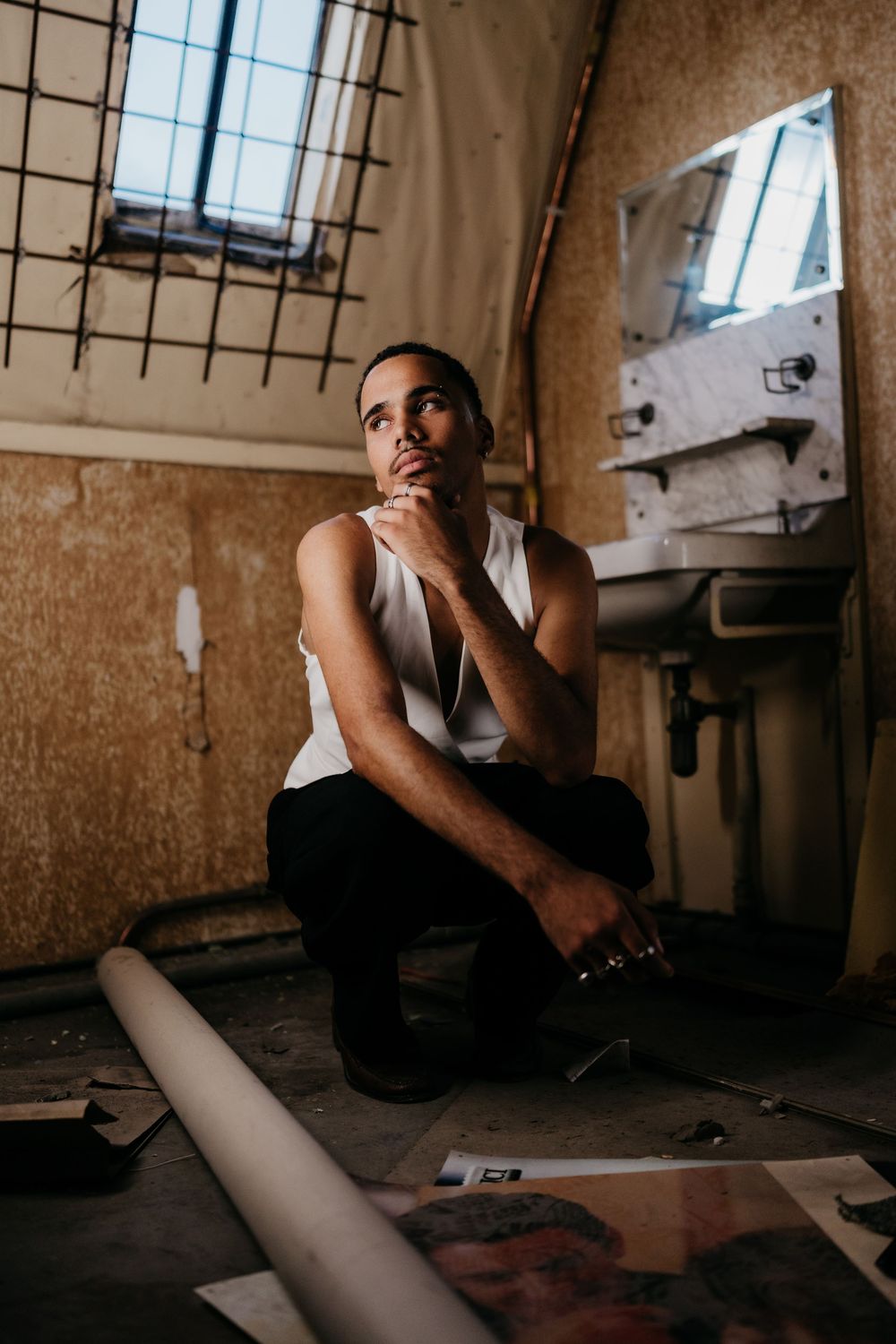 A person sits in contemplative poses against a grungy wall in this moody four-panel photo series.