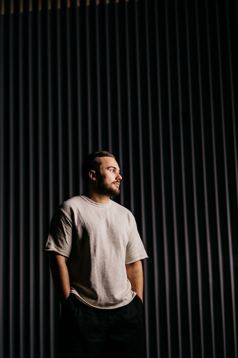 A series of moody portraits against dark striped background showing a person in gray t-shirt turning away from camera.