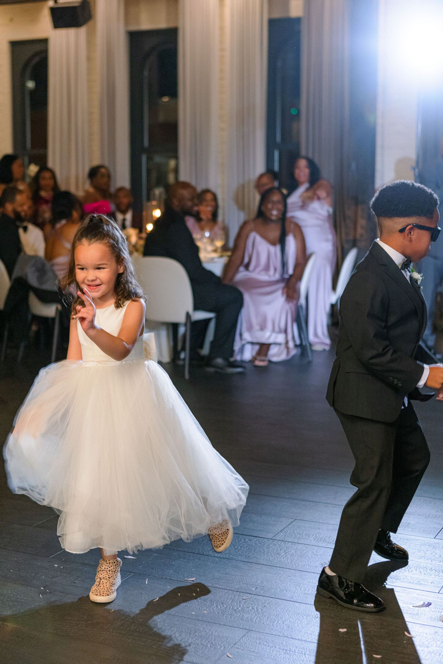 Children in formal wear dancing joyfully at a wedding reception.