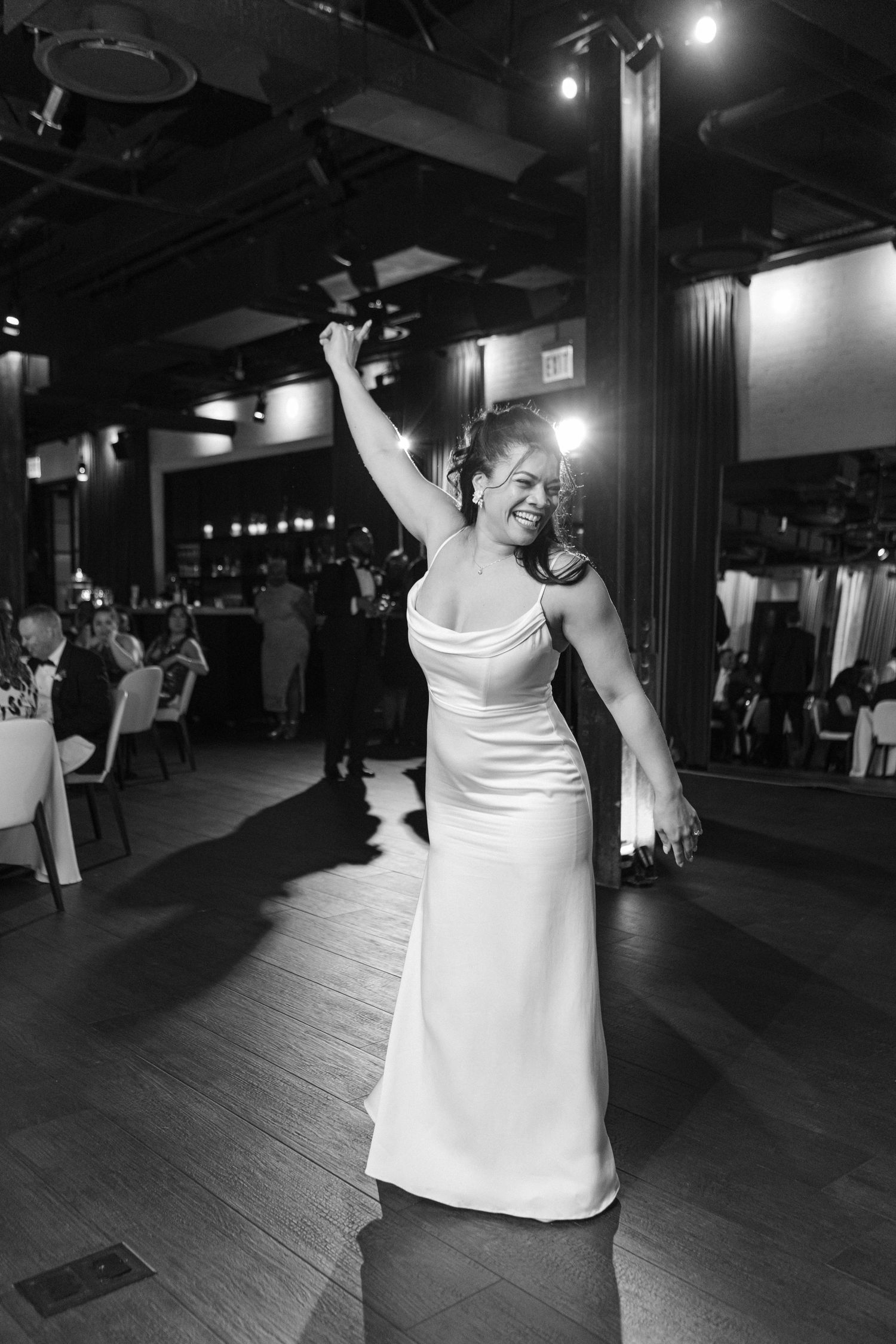 Bride dancing joyfully on the dance floor during wedding reception celebration.