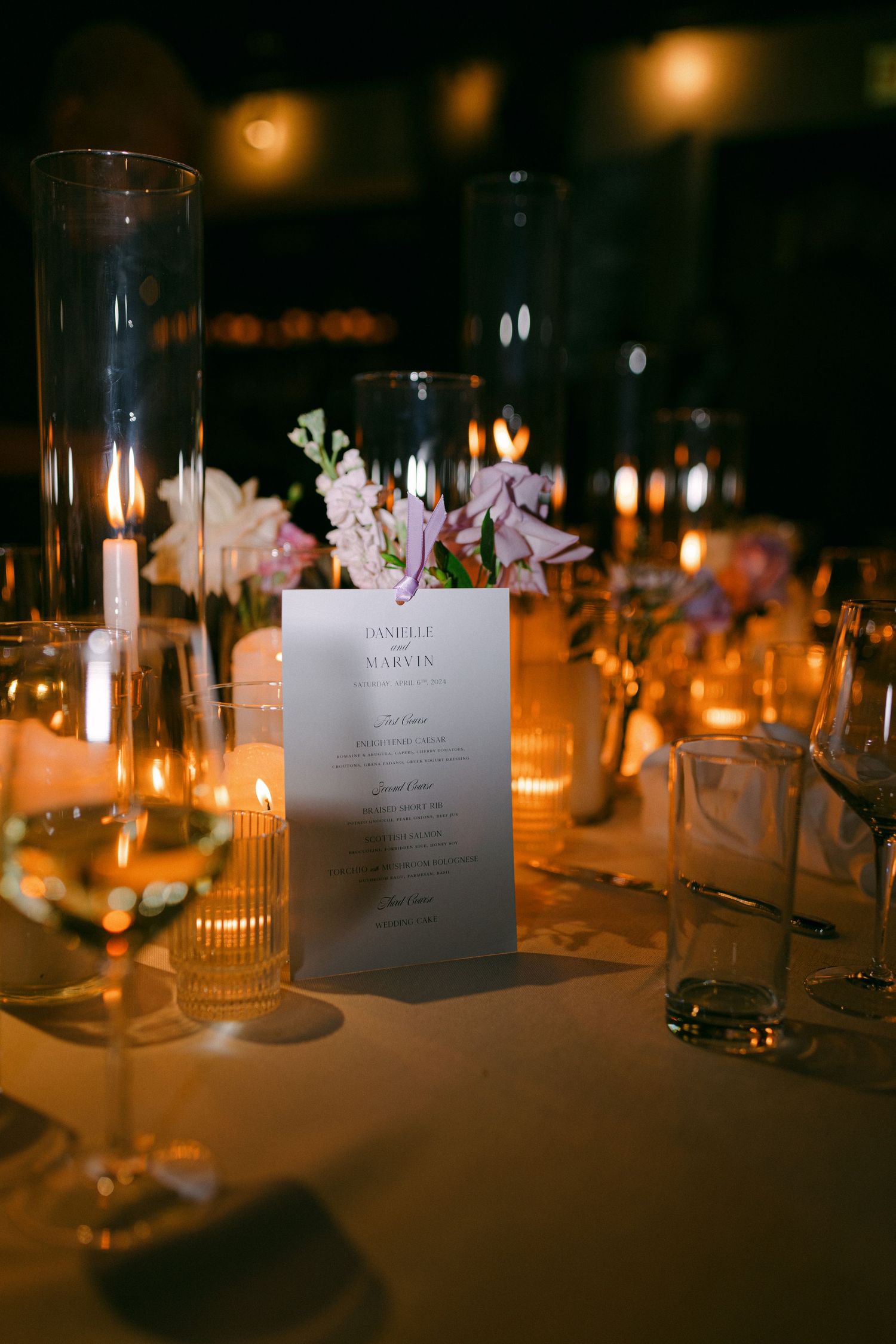 Elegant wedding menu card displayed with floral decorations and candlelight on dining table.
