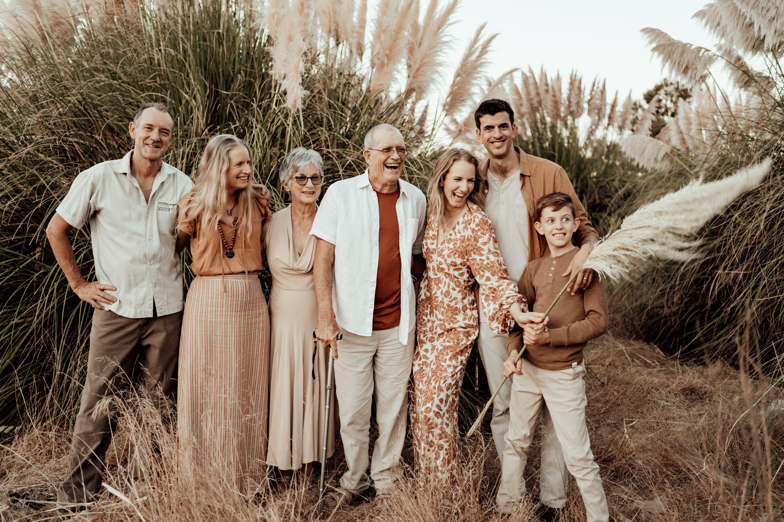 Group portrait of family members in coordinated neutral outfits posed among pampas grass.