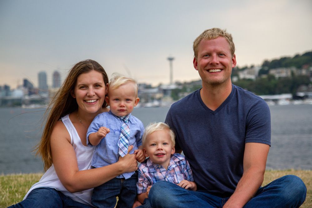 Family portrait outdoors with Seattle Space Needle and skyline visible in background.