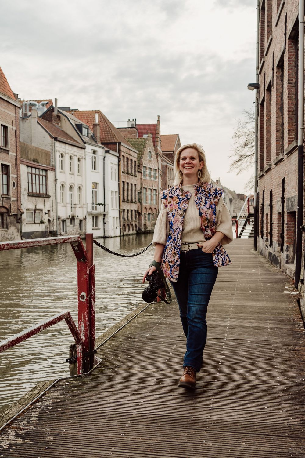 vrouw langs het water in Gent op een soort vlonderpad, fototoestel in de hand