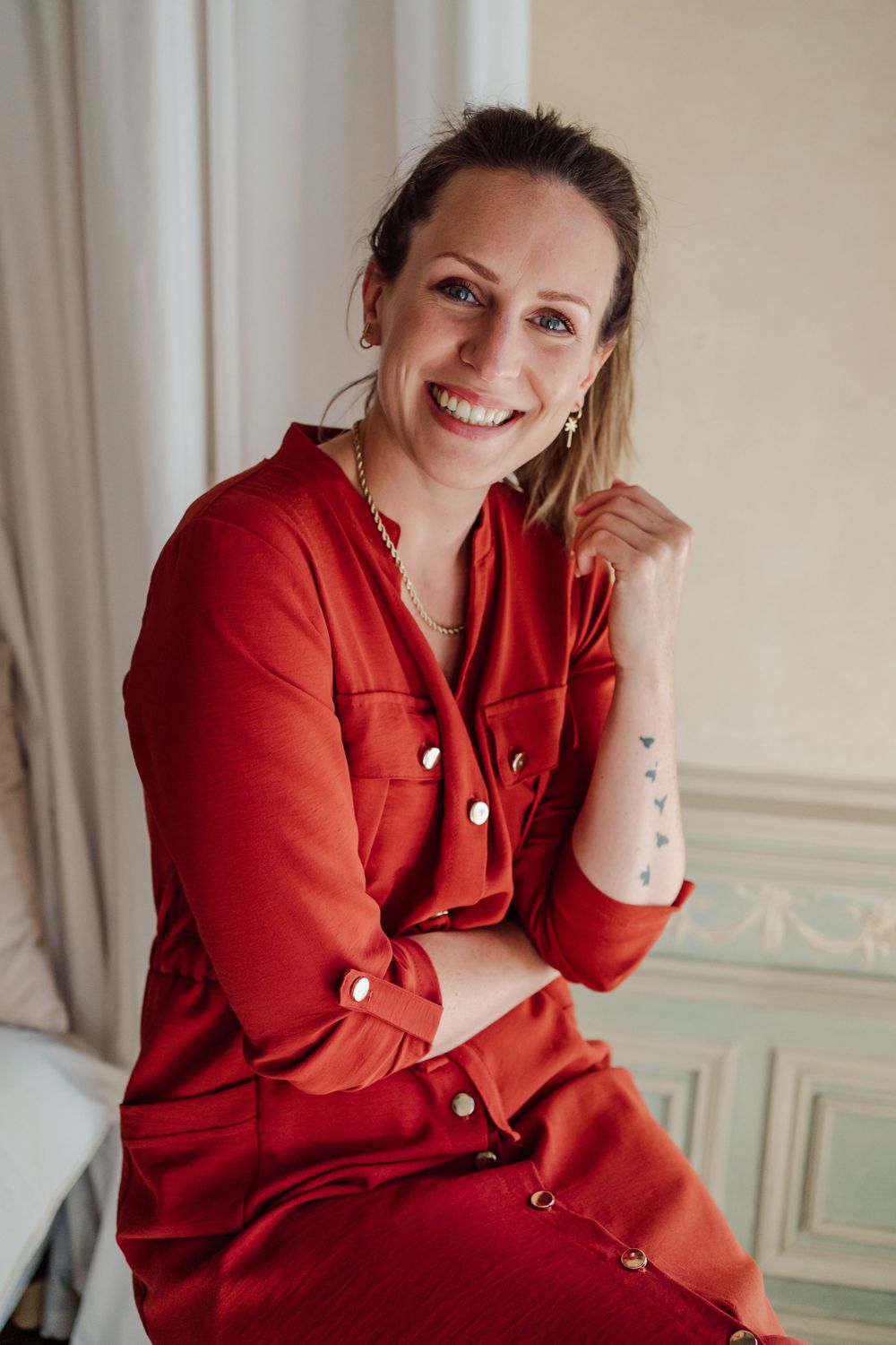 vrouw met rood kleedje zittende op een kruk met hand aan de onderkant van het haar
