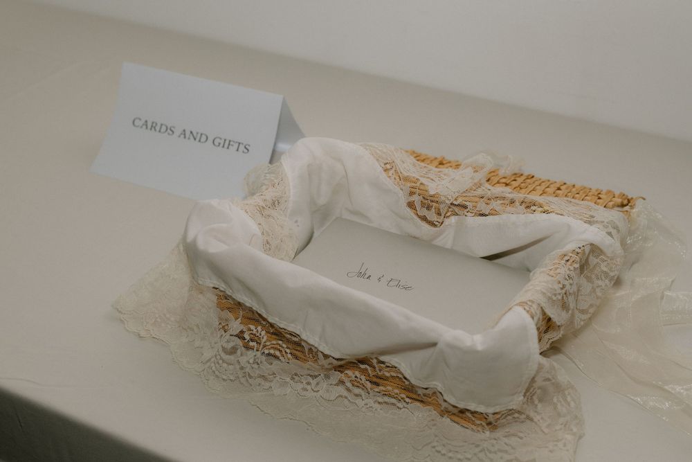A white lace wedding invitation wrapped in delicate fabric.