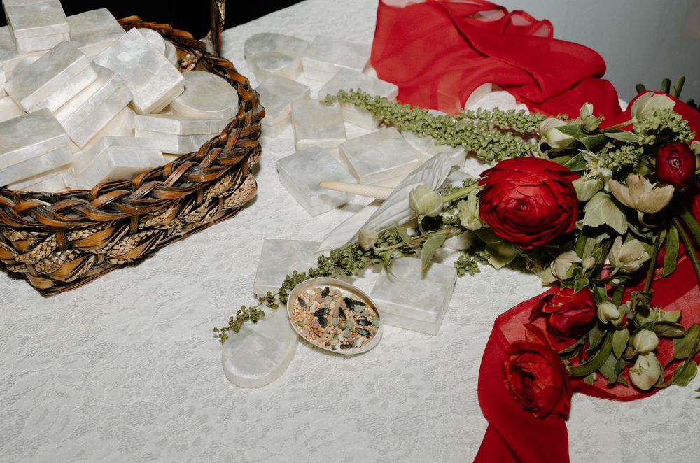 Wedding details including rings, red roses, and white fabric arranged on a textured surface.