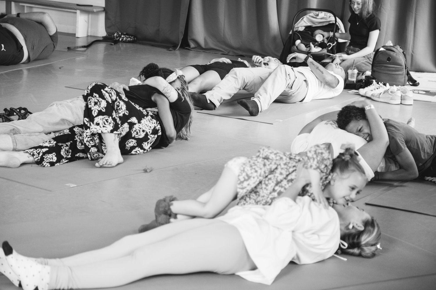 Several dancers resting and stretching on a studio floor during dance practice.