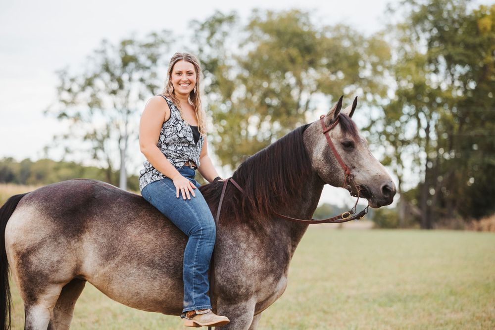 Grey horse and rider enjoying a sunny day in an open field.